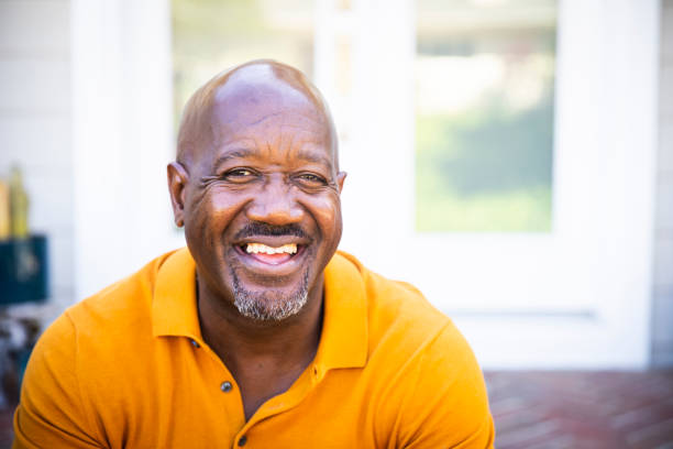 a mature black man looks out while standing on his porch